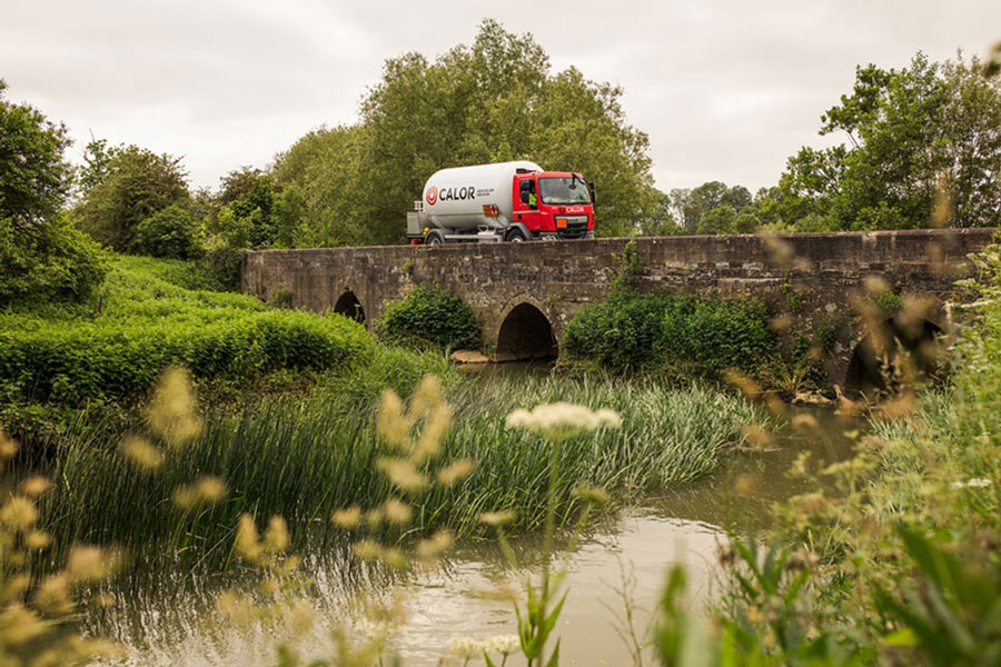 A Calor lorry driving across a bridge in a rural setting _